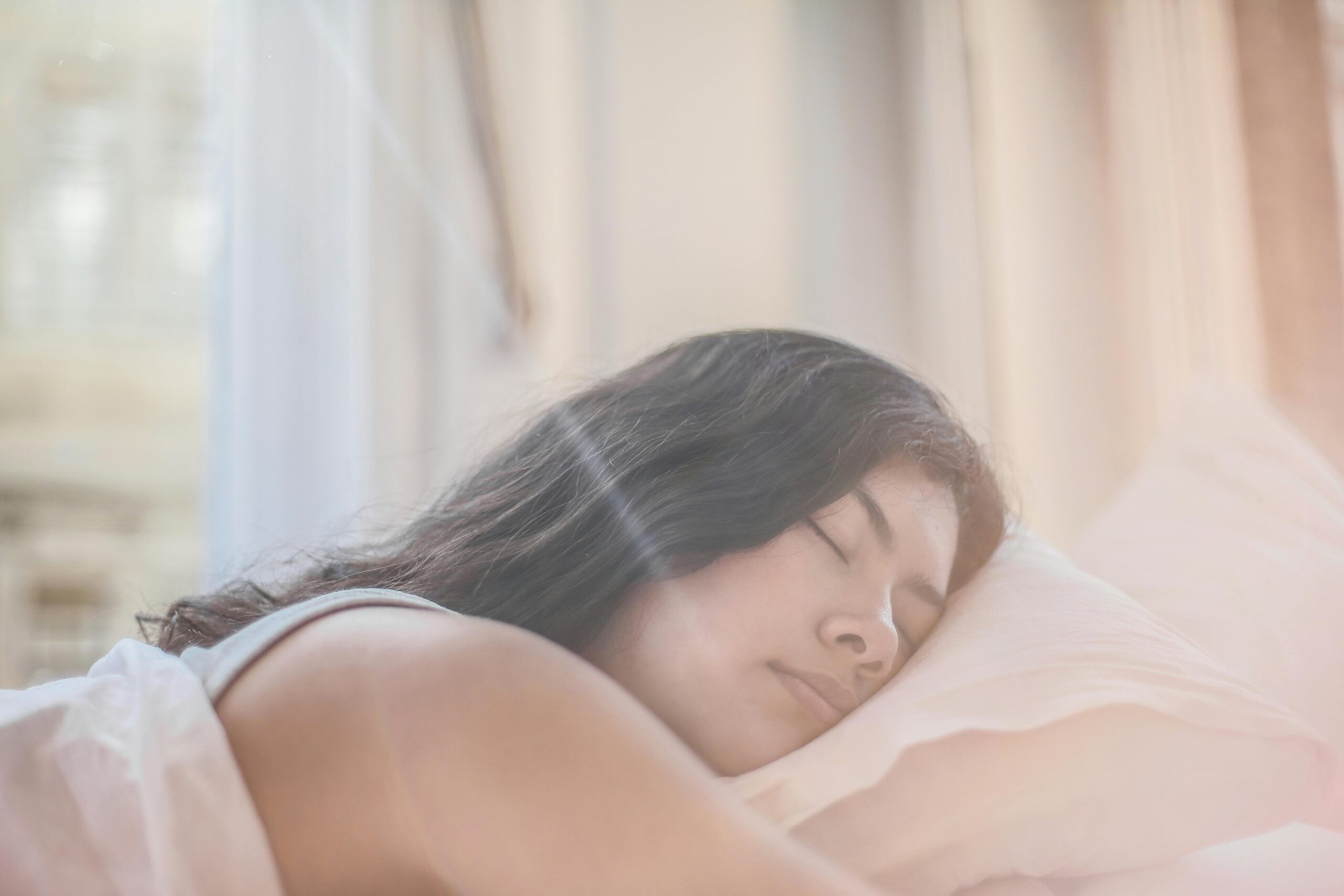 Portrait of a woman sleeping peacefully in soft morning light indoors.