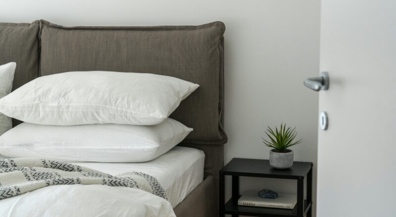 A serene and stylish bedroom featuring a comfortable bed with clean white bedding and a side table with decor.